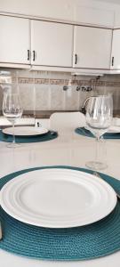 une assiette blanche sur une table avec deux verres à vin dans l'établissement Sesimbra - Praia e Castelo, à Sesimbra