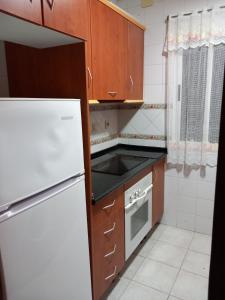 cocina con armarios de madera y nevera blanca en Casa Abuela Antonia, en Granada