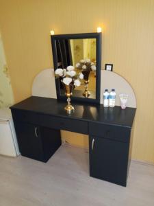 een zwarte dressoir met een spiegel en bloemen erop bij VANNA DELUXE TERMAL HOTEL SPA in Hamamözü