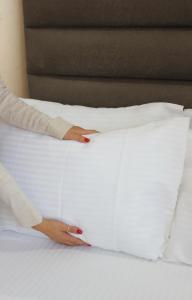 a woman putting her hand on a pillow on a bed at Dem Premium Hotel - Round Trip Airport Service - Istanbul International Airport in Arnavutköy