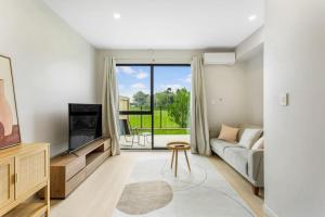 a living room with a couch and a tv at Urban Glow Townhouse with parking in Auckland