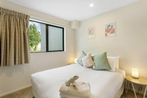 a bedroom with a large white bed with a window at Urban Glow Townhouse with parking in Auckland