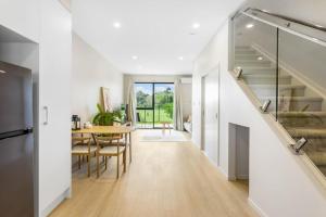 a kitchen and dining room with a staircase and a table at Urban Glow Townhouse with parking in Auckland