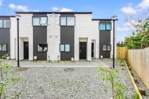 a house with black doors and a fence at Urban Glow Townhouse with parking in Auckland