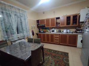 uma cozinha com armários de madeira, uma mesa e um frigorífico em Guest House Ed&Er em Argavand