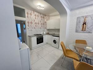 a kitchen with a table and a sink and a dishwasher at New! Supreme Apartment - Near Tube Stations in London