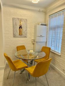 a dining room with a glass table and yellow chairs at New! Supreme Apartment - Near Tube Stations in London