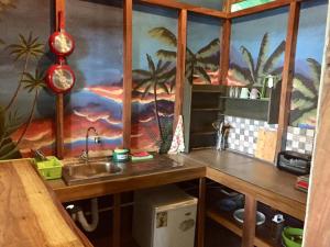 una cocina con fregadero y una pintura en la pared en Oasis Beachfront Hostel, en Puerto Limón
