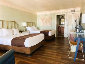 a hotel room with two beds and a desk at Bayfront Inn in St. Augustine