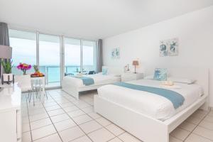 a white bedroom with two beds and a view of the ocean at Girasole Rentals Suites in Miami Beach