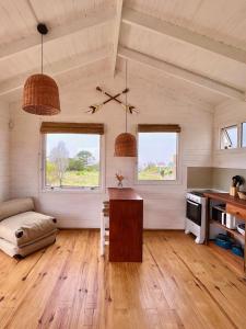 sala de estar con mesa y 2 ventanas en Casitas Punta del Diablo en Punta del Diablo