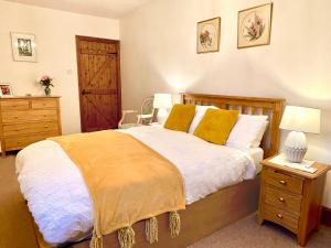 um quarto com uma cama grande e almofadas amarelas em Home Farm Cottage em Barnstaple