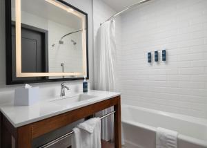 a bathroom with a sink and a tub and a mirror at Four Points by Sheraton San Jose Downtown in San Jose