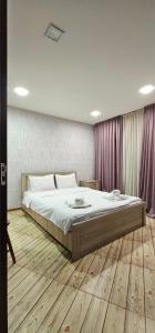 a bedroom with a large bed with wooden floors and purple curtains at 7 Rooms in Tbilisi City