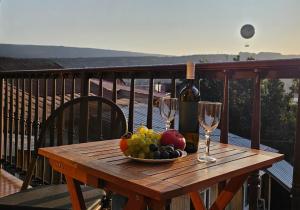a wooden table with a bowl of fruit and wine glasses at 7 Rooms in Tbilisi City