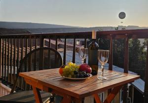 a wooden table with a bowl of fruit and wine glasses at 7 Rooms in Tbilisi City