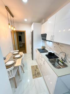 a kitchen with white cabinets and a table and a sink at Lisbon Luxury Studio in Amadora