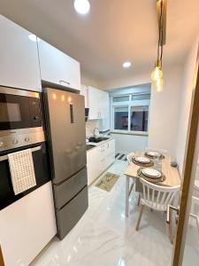 eine Küche mit einem Tisch und einem Kühlschrank aus Edelstahl in der Unterkunft Lisbon Luxury Studio in Amadora