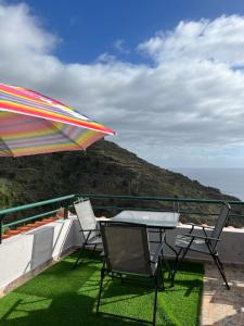 a patio with a table and chairs and an umbrella at Pana House in Calheta
