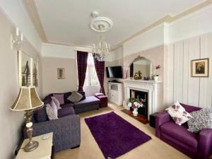 a living room with purple couches and a fireplace at Stoke villas in Gosport