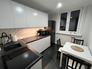 a kitchen with white cabinets and a table and a microwave at Apartament - Classic Olszowa in Włocławek