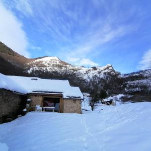 un edificio cubierto de nieve con una montaña nevada en el fondo en Lou cridadé en Laruns