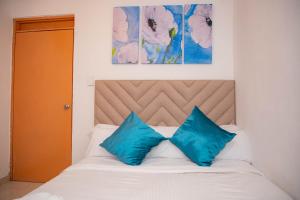 a bed with two blue pillows on top of it at CASA PETRA in Cartagena de Indias