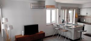 a kitchen with a bar with stools and a television at Sesimbra - Praia e Castelo in Sesimbra