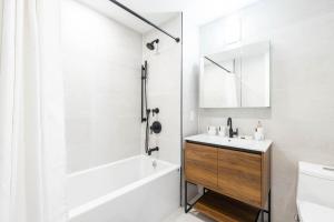 a white bathroom with a tub and a sink at 149BK-202 NEW Condo 1BR IN PRIME GREENPOINT BK in Brooklyn