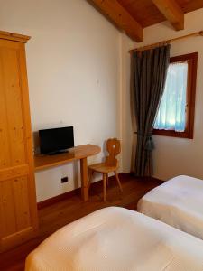 a bedroom with two beds and a desk with a laptop at Agriturismo Busa dei Sbrase 