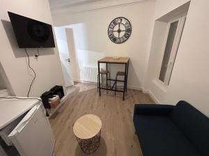 een woonkamer met een bank en een klok aan de muur bij Appartement le petit Royal in Cormelles