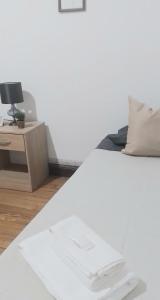 ein Bett mit weißer Bettwäsche und einen Schreibtisch mit einer Lampe in der Unterkunft La Casa de las Flores in Salta