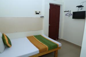 biały pokój z łóżkiem z brązowymi drzwiami w obiekcie ROYAL GREEN AIRPORT TRANSIT ACCOMMODATION w mieście Ćennaj