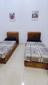 淡馬魯的住宿－Humairah Homestay - Near Bandar Temerloh，两张睡床彼此相邻,位于一个房间里