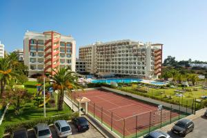 una pista de tenis en un aparcamiento con edificios en Ukino Palmeiras Village - 24h All Inclusive, en Armação de Pêra