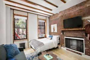 Habitación con pared de ladrillo, cama y chimenea. en 24-6 Gramercy area Newly reno Studio W D in unit en Nueva York