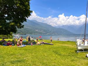 a group of people sitting on the grass near a lake at Lago Lodge Claudia in Domaso