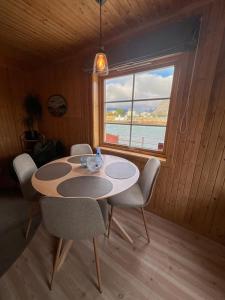 a dining room with a table and chairs and a window at Rostad Retro Rorbuer in Reine