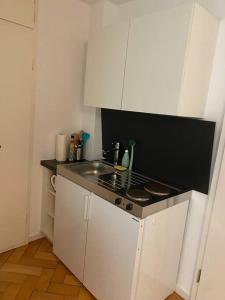 a small kitchen with a stove and white cabinets at Ferienwohnung „Marina“ im Schwarzwald in Lörrach
