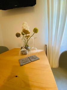 a wooden table with two vases and flowers on it at Ferienwohnung „Marina“ im Schwarzwald in Lörrach