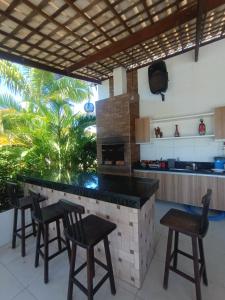 een keuken met een bar met stoelen en een televisie bij Casa Girassol FG in Aracaju