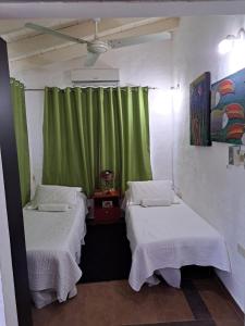 two beds in a room with a green curtain at Mini casa en el mirador San Bernardino. Guarania in San Bernardino