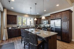 a kitchen with wooden cabinets and a large island with bar chairs at Paradise Village at Zion 28 Private Hot Tub, Outdoor firepit, and Community Pool in Santa Clara