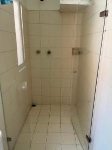 y baño con ducha de azulejos blancos. en Casa Grande Hostal, en Medellín
