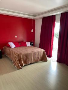 a bedroom with a bed with red walls and a window at Casa completa com piscina no Paraíso do Brasil in Governador Celso Ramos