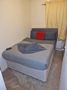a bed in a bedroom with a red pillow on it at KO 3 bed house in Kent