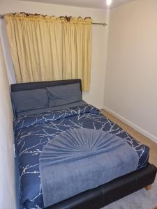 a bedroom with a bed with a blue comforter and a window at KO 3 bed house in Kent