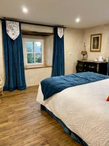 若瑟蘭的住宿－Une nuit chez une artisane，一间卧室配有一张带蓝色窗帘的床和一扇窗户