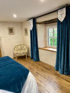 een slaapkamer met blauwe gordijnen, een bed en een raam bij Atelier Corinne G : la chambre 9 in Josselin
