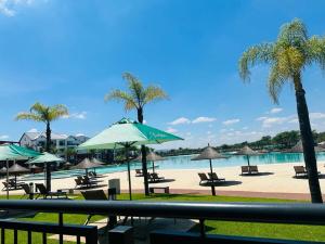 una playa con sillas y sombrillas y una piscina en The Blyde Crystal Lagoon, en Pretoria